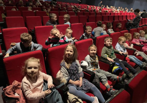dzieci siedzą na widowni w sali teatralnej