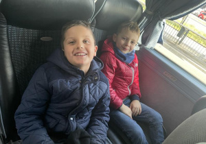 dwoje dzieci siedzących na miejscach w autokarze