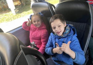 dwoje dzieci siedzących na miejscach w autokarze