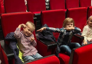 Dzieci siedzące na widowni w teatrze, chłopcy pozują do zdjęcia