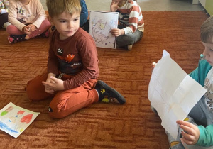 Dzieci na dywanie trzymają kartki