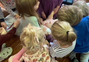 Dzieci na dywanie udzielają pierwszej pomocy małej lalce fantomowej