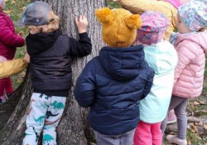 Dzieci z nauczycielką próbują przewrócić drzewo