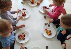 Dzieci jedzą urodzinowy torcik owocowy