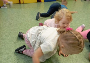 Dzieci poruszają się na czworakach. Za pomocą oddechu wprawiają w ruch piłeczki pingpongowe