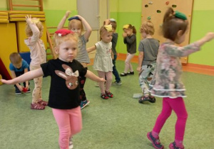 Dzieci wykonują ćwiczenie równoważne chodząc z woreczkami gimnastycznymi położonymi na głowach