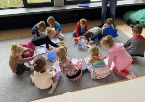 dzieci siedzą na dywanie i rysują