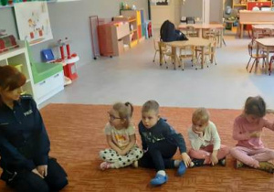 Dzieci siedzą na dywanie razem z Panią Policjantką.