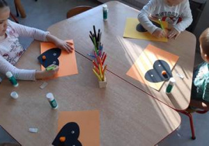 Dzieci przyklejają na karton serce i rysują kolce wokół niego.