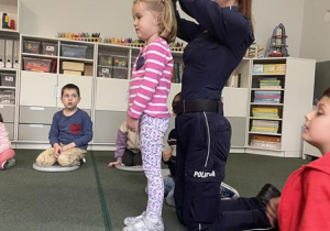 pani policjantka prezentuje z dziewczynką pozycję żółwia na wypadek ataku psa
