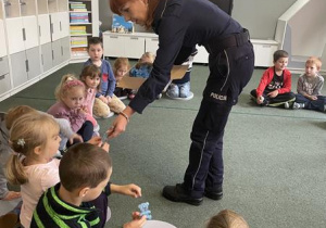 policjantka wręcza dzieciom odblaskowe misie