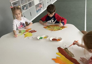 dzieci malują farbami duże liście z papieru