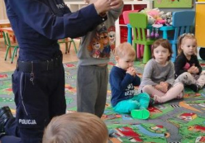 Pani policjantka pokazuje dzieciom, w jaki sposób spleść dłonie do pozycji żółwia