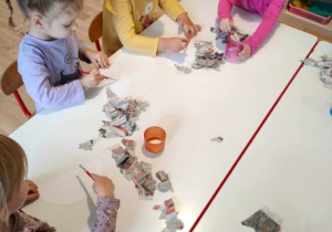 Dziewczynki przyklejają kawałeczki gazety na białe półkola