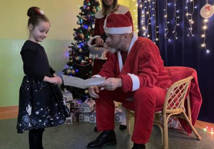 Dziewczynka wręcza Mikołajowi rysunek