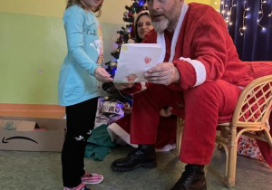 dziewczynka wręcza rysunek Mikołajowi