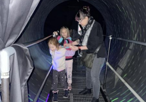 dzieci z nauczycielką przechodzą przez kładkę w ruchomym tunelu