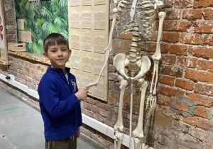 chłopiec trzyma za rękę ludzki szkielet