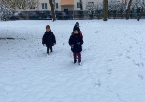 Chłopcy w ogrodzie przedszkolnym bawią się śniegiem