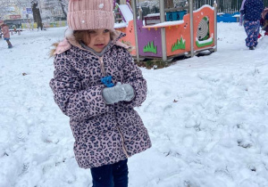 Dziewczynka w ogrodzie przedszkolnym lepi śnieżkę