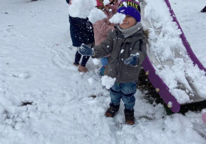 Dzieci w ogrodzie przedszkolnym rzucają się śniegiem