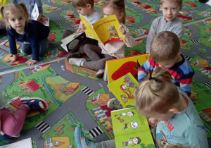 Dzieci oglądają książki na dywanie