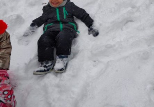 Uśmiechnięty chłopiec przysiadł na śniegu