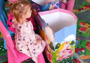 Dziewczynka wybiera sobie upominki z kolorowych torebek stojących przed jubilatkami