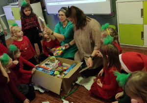 Nauczycielki wyjmują zabawki z pudła i pokazują je dzieciom.