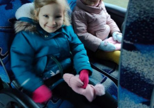 Dziewczynki uśmiechają się do zdjęcia siedząc w autokarze