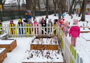 Dzieci przyglądają się pokrytemu śniegiem ogródkowi warzywnemu