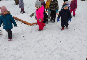 Dzieci spacerują po zimowym ogrodzie przedszkolnym