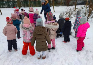 Dzieci z nauczycielką przyglądają się śladom na śniegu