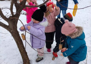 Dzieci wieszają na drzewie karmidełka dla ptaków