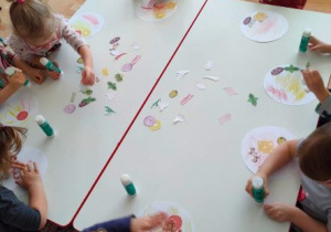 Dzieci wyklejają szablony pizzy papierowymi składnikami