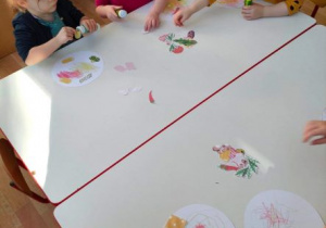 Dziewczynki przyklejają składniki pizzy na papierowych kołach