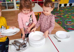 Dzieci biorą talerze i łyżki, by nakryć sobie do posiłku