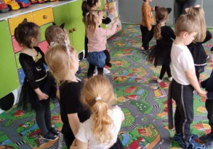 Dzieci tańczą w parach koci taniec. Nauczycielka demonstruje pokazywanie kocich pazurków