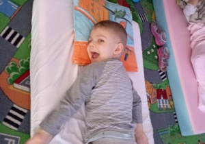 Chłopiec śmieje się leżąc na brzuchu na materacu