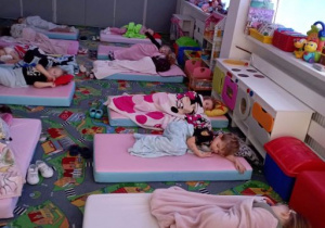Dzieci leżą na materacach podczas poobiedniego odpoczynku