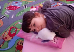 Dziewczynka przytula swoją maskotkę leżąc na materacu