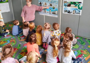 Nauczycielka opowiada dzieciom o zwierzętach klimatu zimnego wskazując ilustrację foki