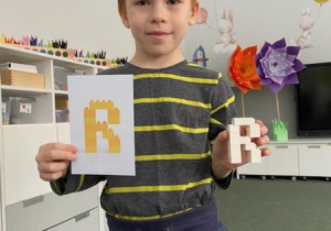 chłopiec pokazuje skonstruowaną z klocków literę R