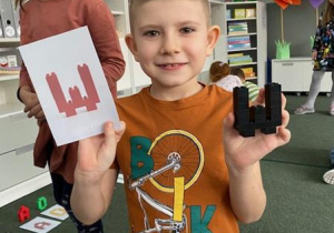 chłopiec pokazuje skonstruowaną z klocków literę W