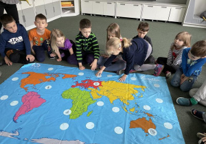dzieci dopasowują obrazki zwierząt do środowisk życia na mapie świata