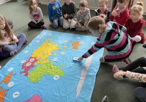 dzieci dopasowują obrazki zwierząt do środowisk życia na mapie świata