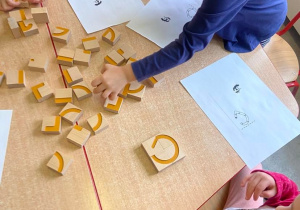 Dzieci układają literę "s" z drewnianych klocków