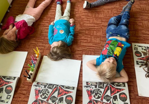Dzieci na dywanie leżą z zamkniętymi oczami
