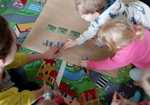 Dzieci układają na rysunku drzewa zdjęcia bobrów, którym drzewa służą do budowania żeremi
