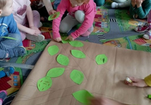 Dziewczynka przykleja listek na koronie narysowanego drzewa